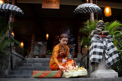 The woman sitting next to bust and umbrella
